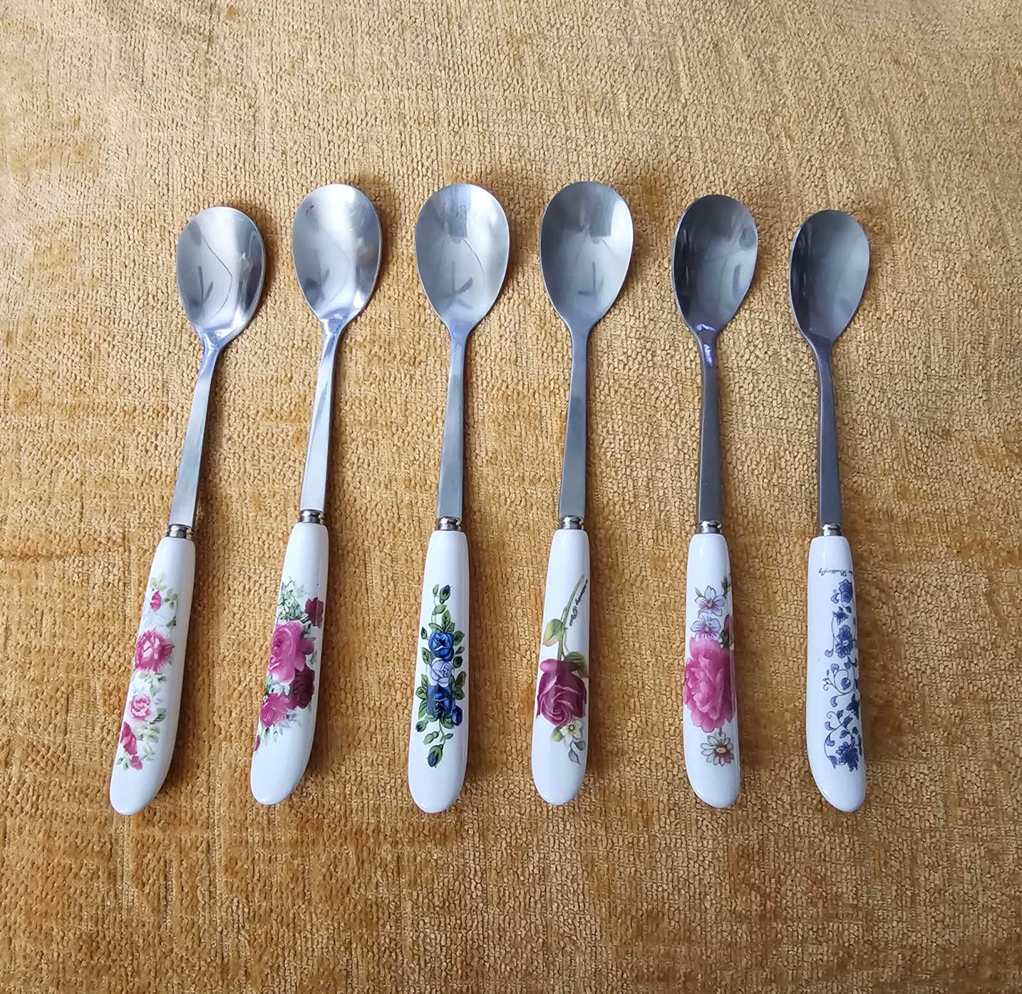 Six metallic  spoons with floral-patterned handles arranged successful  a row