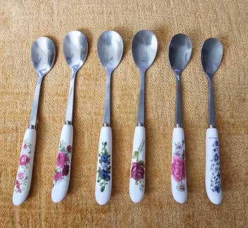Six metallic spoons with floral-patterned handles arranged successful a row