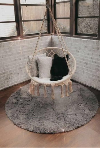 Reviewer photo of the round grey rug under a hanging chair