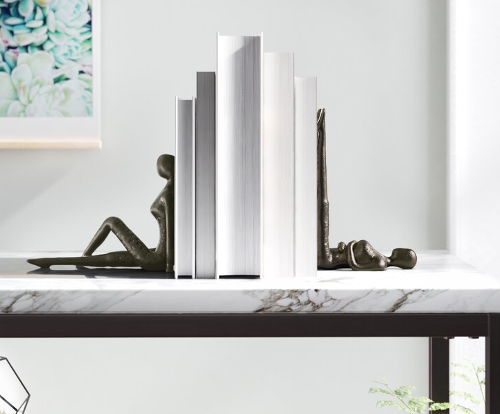 the black figure bookends sandwiching a stack of books 