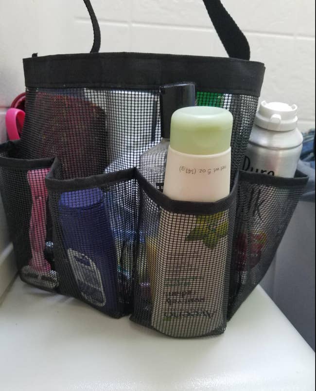 black mesh round shower caddy bag with items in it 