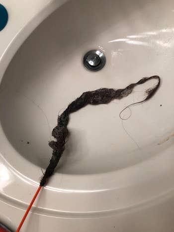 reviewer photo of hair hanging off of a drain snake in a sink