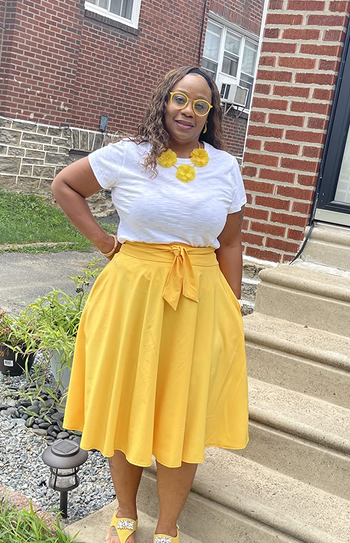 Reviewer is wearing a white top and bright yellow skater midi skirt