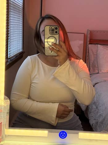 Person taking a reflector  selfie portion    wearing a long-sleeve top, with chamber  decor disposable   successful  the background