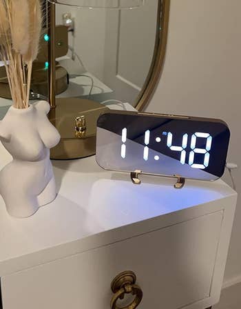 reviewer's rotating clock on a gold base next to other decor