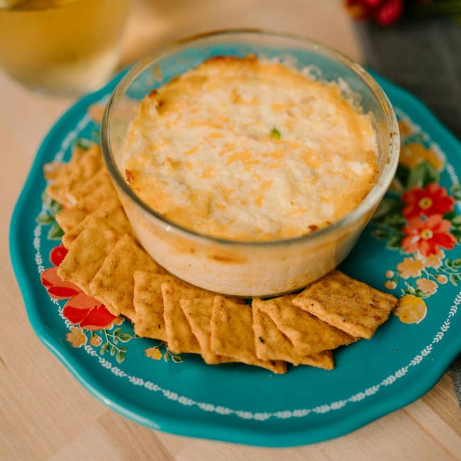 Baked food dip successful a solid crockery surrounded by crackers connected a decorative plate. Ideal for entertaining oregon snacking