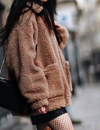 Model in a zippered camel colored faux shearling jacket 