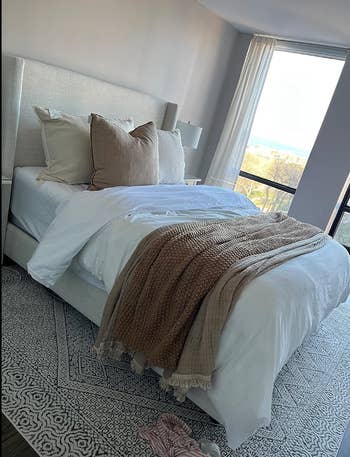 A wide shot of the white sheets on a bed under a duvet 