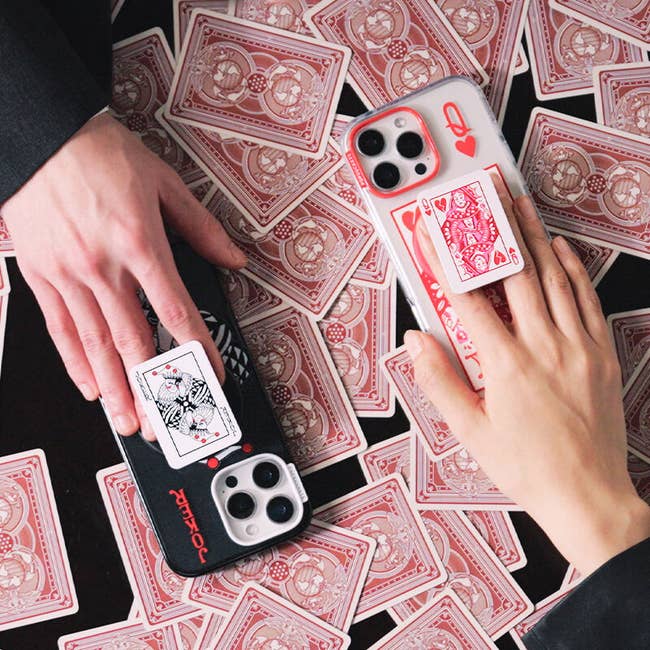 Two hands clasp  smartphones with playing card-themed popular  up   charms 