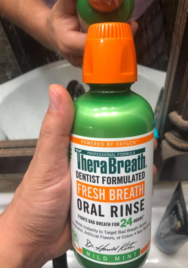 reviewer holding bottle of the oral rinse