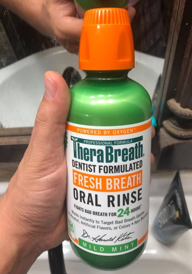 reviewer holding bottle of the oral rinse