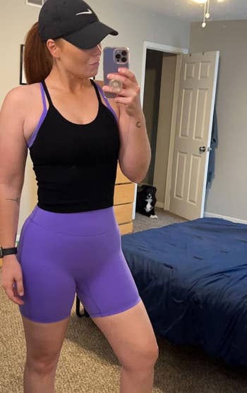 reviewer wearing the black top over a purple workout outfit