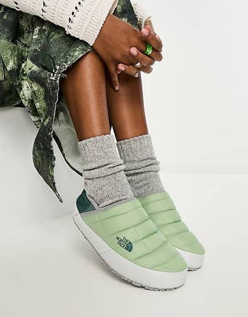 a model wearing the green slippers