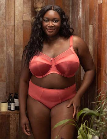 Model wearing stylish coral lingerie set, posing successful  a rustic mounting  with skincare products successful  the background