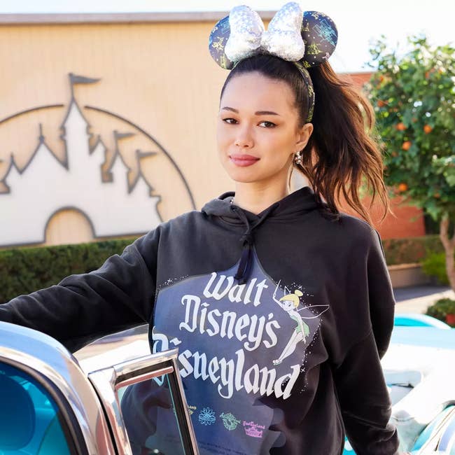 a model on a black hooded sweatshirt with walt disney's disneyland on it and tinkerbell 