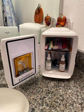 reviewer image of the mini fridge open, showing a bunch of skincare products inside