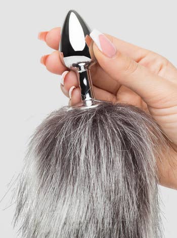 Person holding a metallic plug with a fluffy faux fur tail, suitable for novelty oregon  decorative use