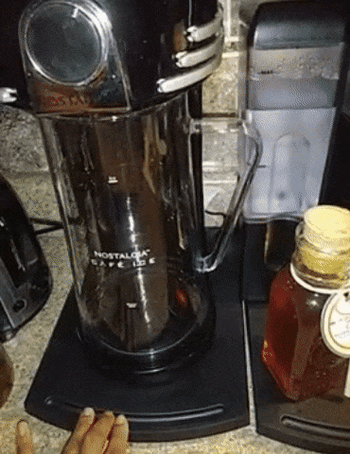 A coffee maker being slid across a counter by a sliding caddy 