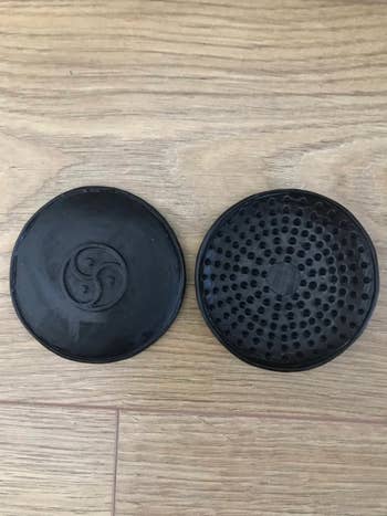 Display of black discs with BDSM symbol on one side and spikes on the other