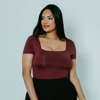 A model posing in the red wine bodysuit with black jeans