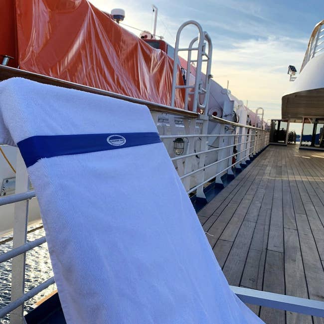 White towel with a logo, draped on a railing aboard a ship with deck visible