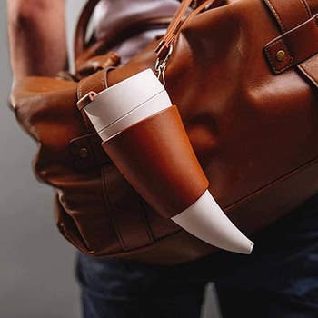 Person carrying a brown bag with a novelty cup shaped like a horn attached to it