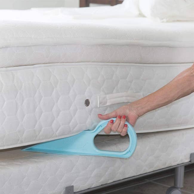 hand pushing the blue plastic wedge under a mattress