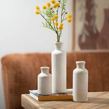 A set of three white cylinder shaped vases in different sizes 