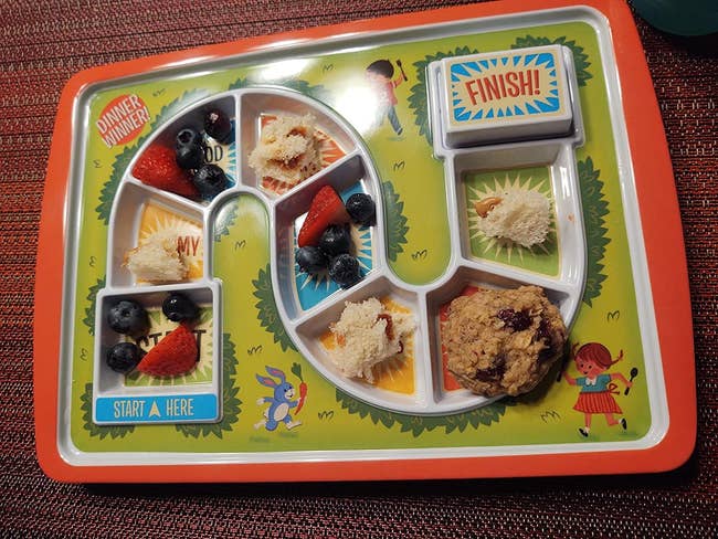 A reviewer's plate filled with various foods in the different compartments