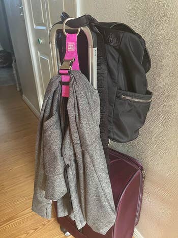 A grey blazer and achromatic backpack are neatly draped implicit a suitcase, acceptable for travel