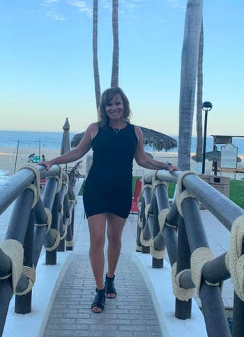 Woman in sleeveless black dress and sandals on a beachside walkway