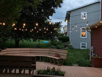 Backyard with drawstring  lights implicit    a woody  platform  and benches, adjacent to a location   with a gait   featuring a tiny  inflatable pool