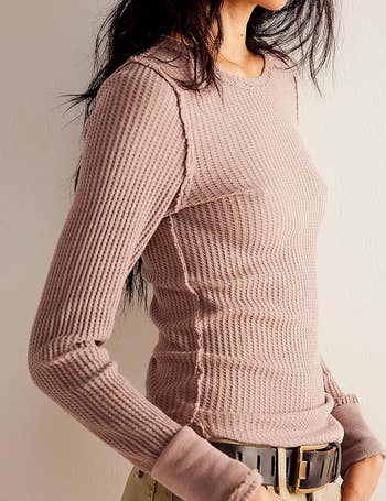 Person wearing a fitted ribbed long-sleeve garment with textured detailing and a belt