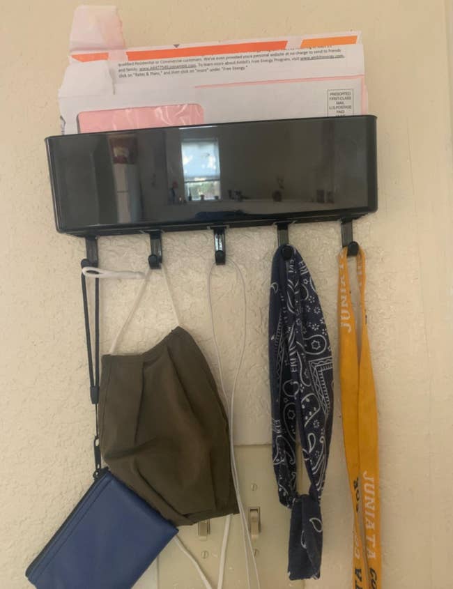 reviewer photo of the organizer on a wall holding a wallet, a face mask, and a bandana on the hooks and mail in the box