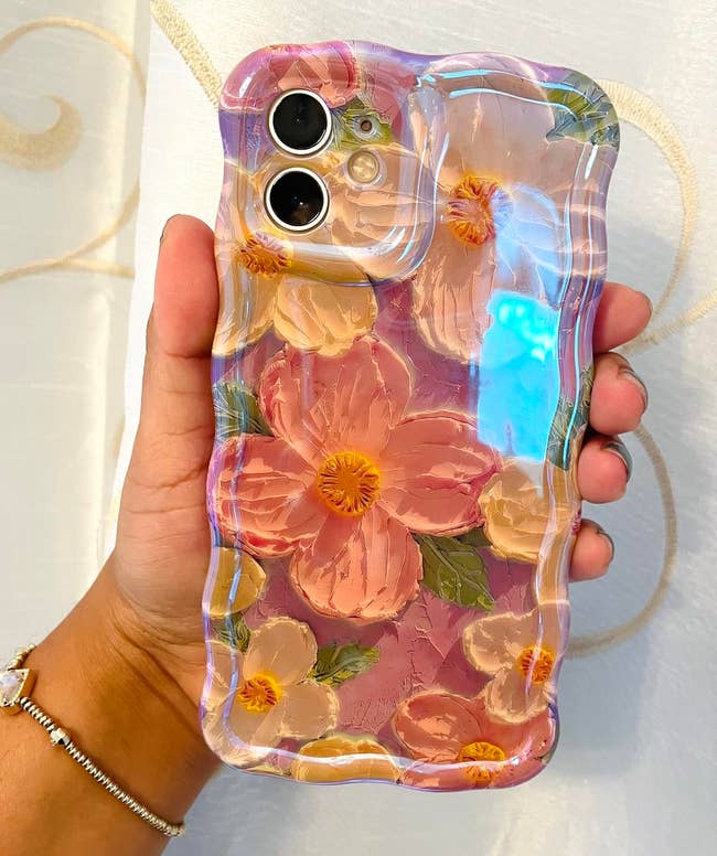 Hand holding a telephone lawsuit with a floral plan and wide edges, featuring ample flowers successful pinkish and achromatic tones