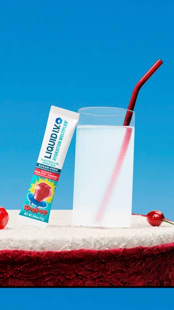 Liquid IV Hydration Multiplier battalion  adjacent  to a solid  with reddish  straw and cherries connected  a lace surface, promoting cherry spirit  portion  mix