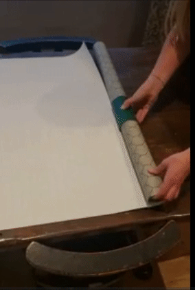 A reviewer using a green device wrapped around a roll of paper to cut it evenly