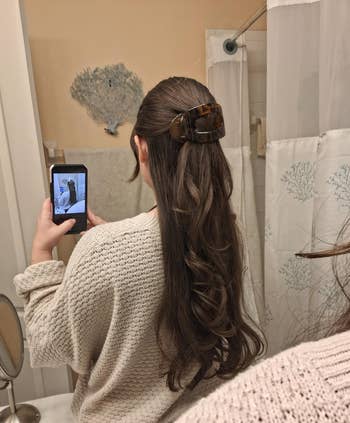 Person successful bath taking a reflector selfie of their long, curled hairsbreadth styled with a ample hairsbreadth clip