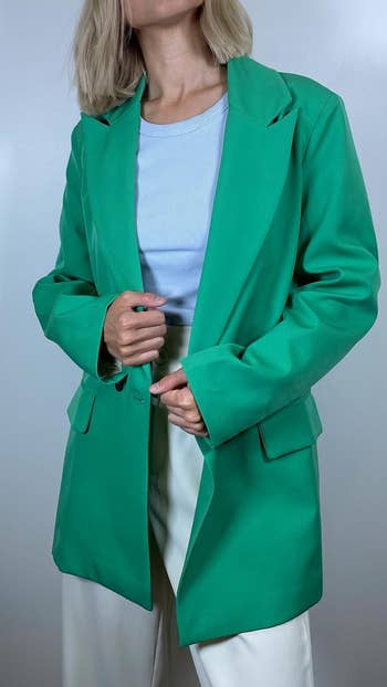 a reviewer in a green blazer and white pants
