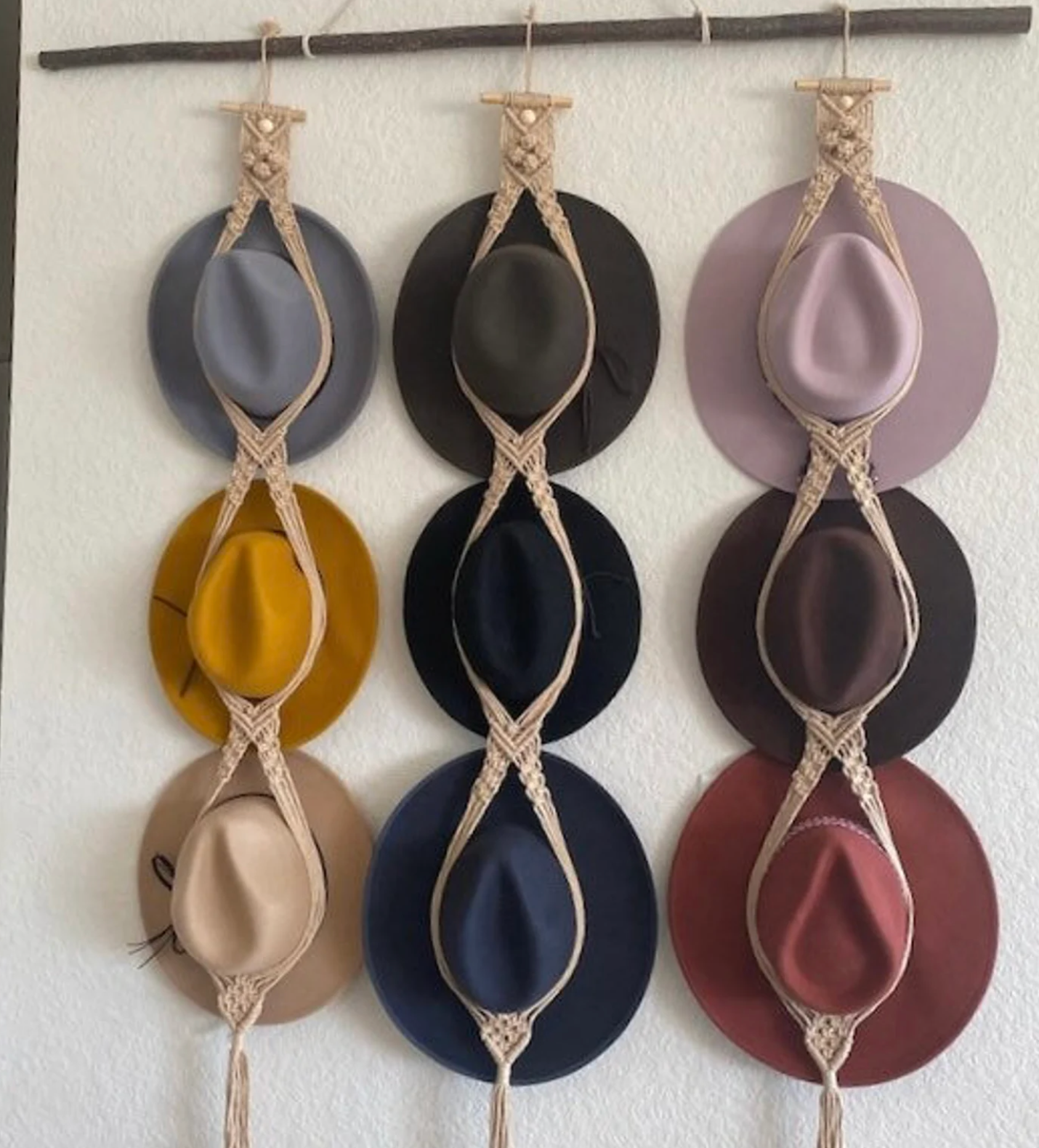 nine hats in various colors hanging on a macrame hat organizer