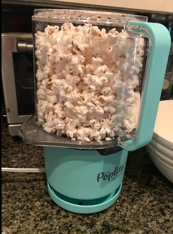 A countertop air popper filled with freshly popped popcorn, labeled 