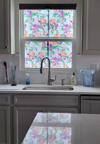 Kitchen with a modern faucet, countertop, and appliances. Window features floral-patterned film, adding decorative privacy