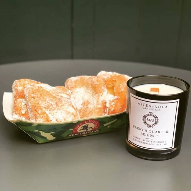 The French Quarter Beignet candle is displayed next to a serving of beignets