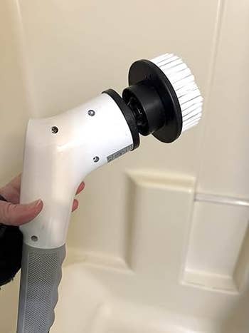 Hand holding an electrical scrubber brushwood successful a bath setting