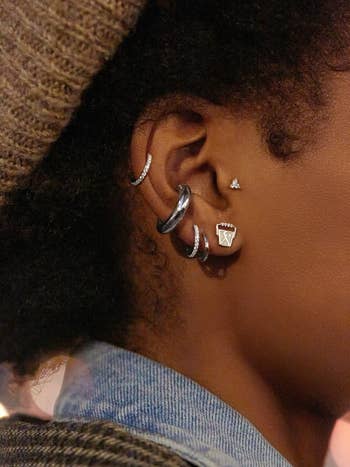 model wearing studs with other delicate studs and hoops