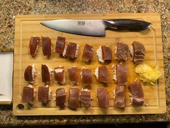 Sushi pieces arranged neatly connected  a woody  cutting committee  with a chef's weapon  and a tiny  heap  of pickled ginger beside them