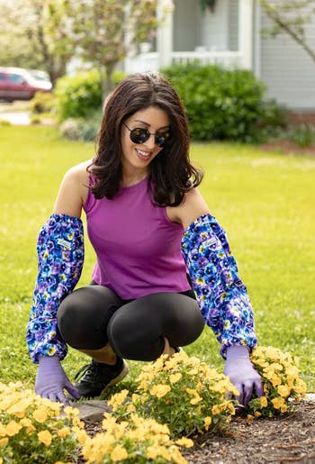 Woman in sunglasses and floral sleeve top gardening among yellow flowers