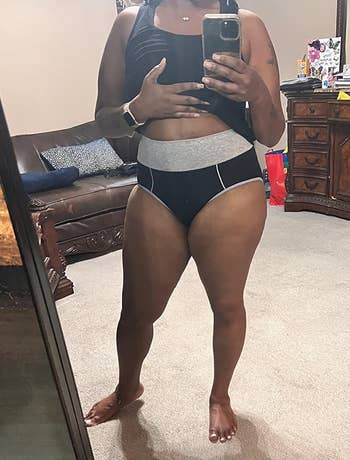 Person successful a reflector selfie wears a vessel apical and underwear with a supportive waistband, successful a homely bedroom