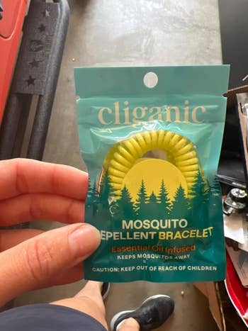 Reviewer holding an individually packaged mosquito repellent bracelet