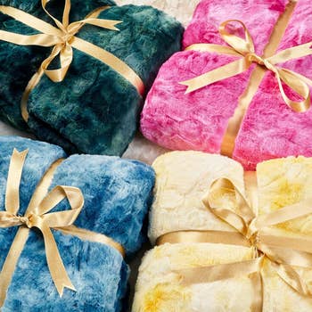 The green, pink, blue, and yellow blankets folded up and tied with bows for gifting